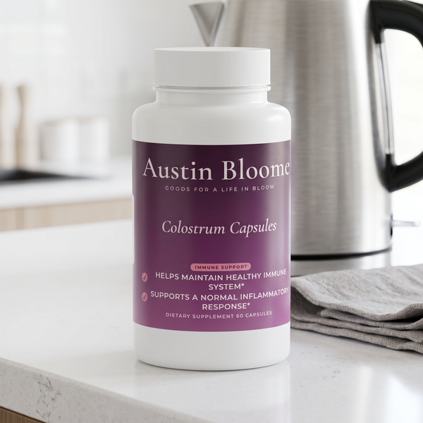 Colostrum Capsules on a bright white kitchen counter beside a kettle