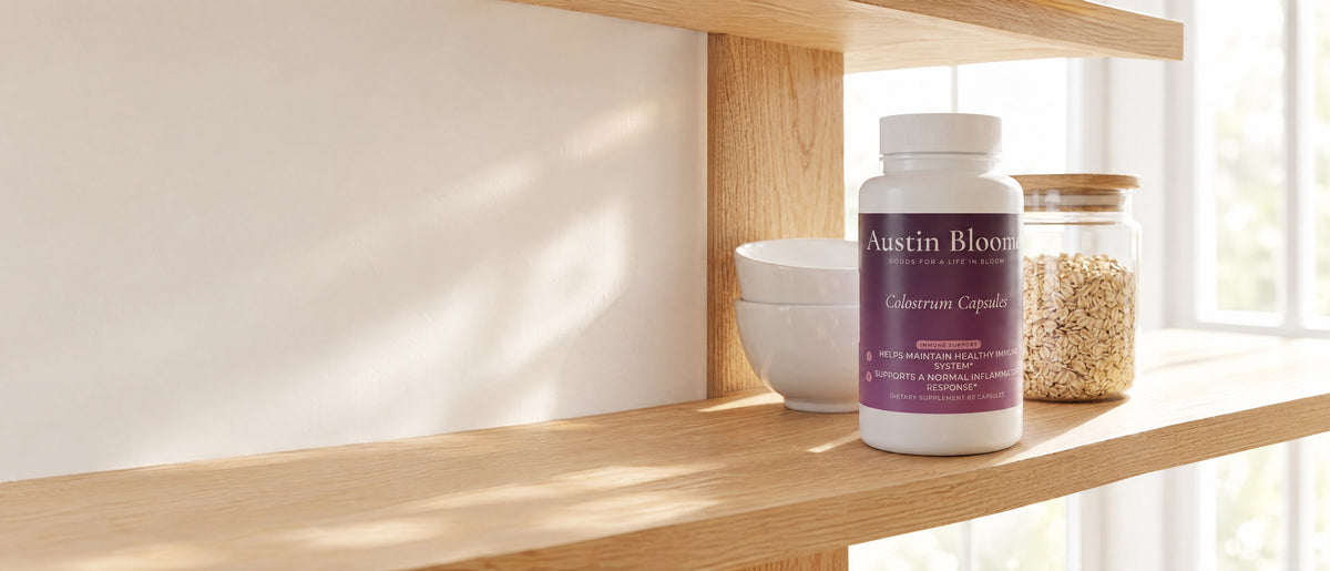Colostrum Capsules bottle on a sunlit oak kitchen shelf beside white bowls and a jar of oats