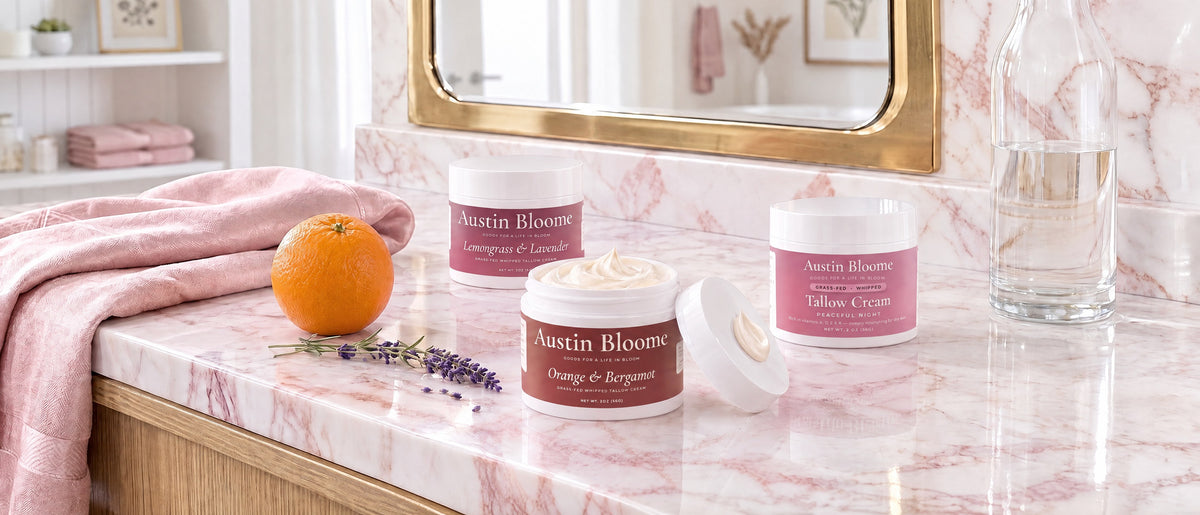 Tallow Ancestral Skincare Trio: Lemongrass & Lavender, Orange & Bergamot and Peaceful Night whipped tallow creams on a blush marble vanity with an orange and lavender