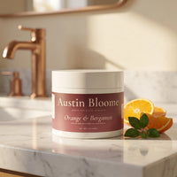 Tallow Cream Orange & Bergamot jar on a white marble bathroom benchtop with copper tapware