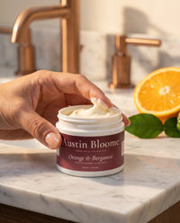 Fingertip scooping Orange & Bergamot tallow cream from the jar