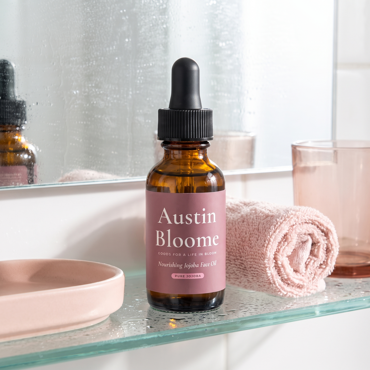 Nourishing Jojoba Face Oil on a dewy bright bathroom shelf with a blush towel